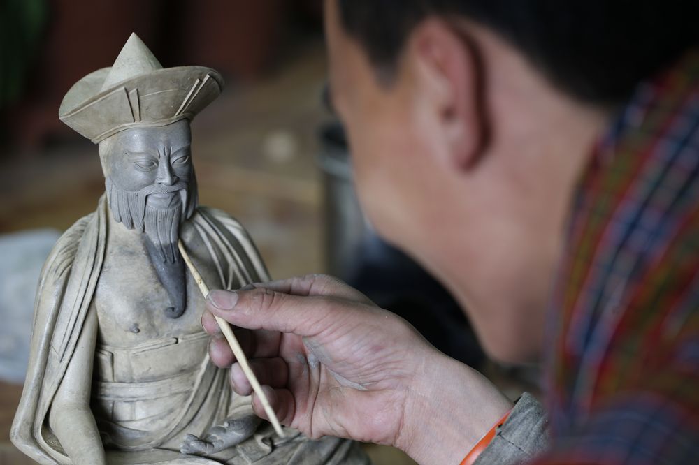 A Bhutanese artisan hand-finishing a traditional clay statue