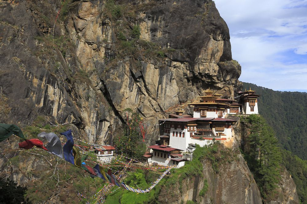 Prayer flags strung below Paro Taktsang, the Tiger's Nest Monastery