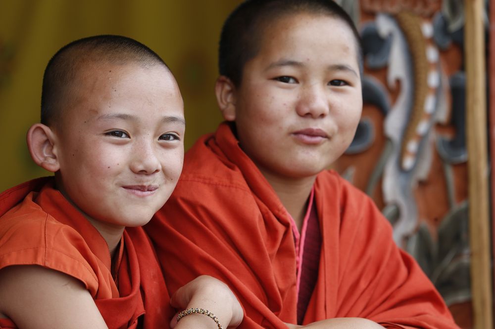 Two young monks smiling warmly at a Bhutanese monastery